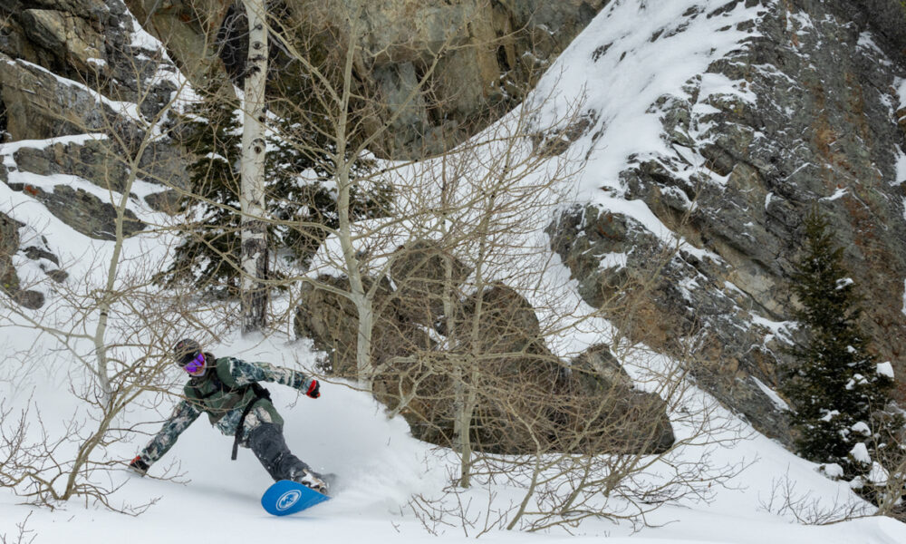 Snowboarder riding steep rocky terrain in the Jackson Hole backcountry.