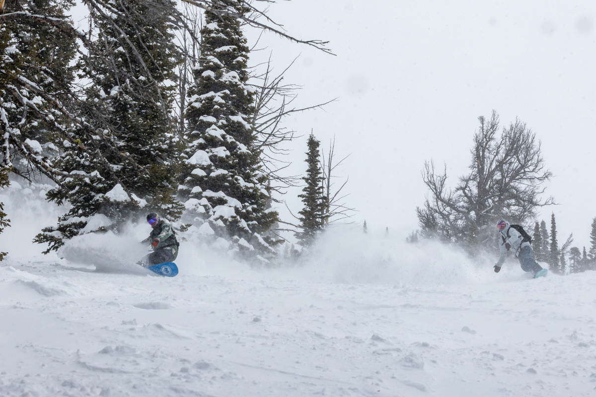 Snowboarder deep in powder spray during a Union Atlas binding test.