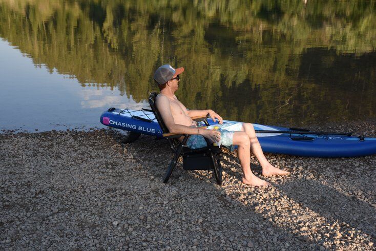 Man Sitting Next to Paddle Board