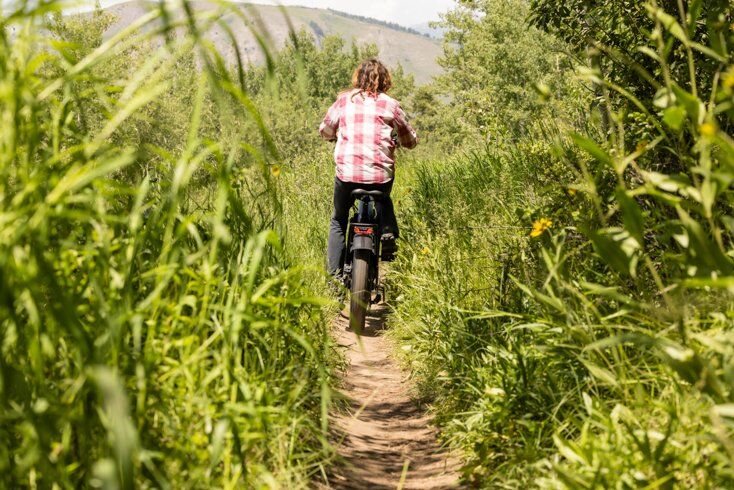 Women Riding E-Bike with Tall Grass