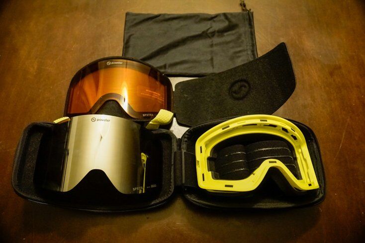 The packaging includes (from top to bottom) a soft case, spare lens and lens holder, hard case, goggles, and 6% VLT Cosmic Silver lens.