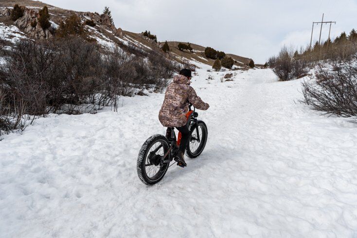 Man Riding Uphill on Snow on an E-Bike
