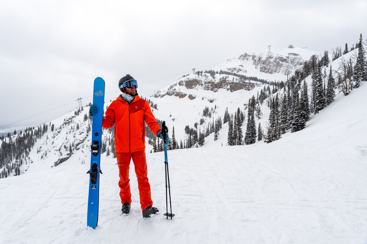 Man Standing Next to Skis in Red Ski Suit