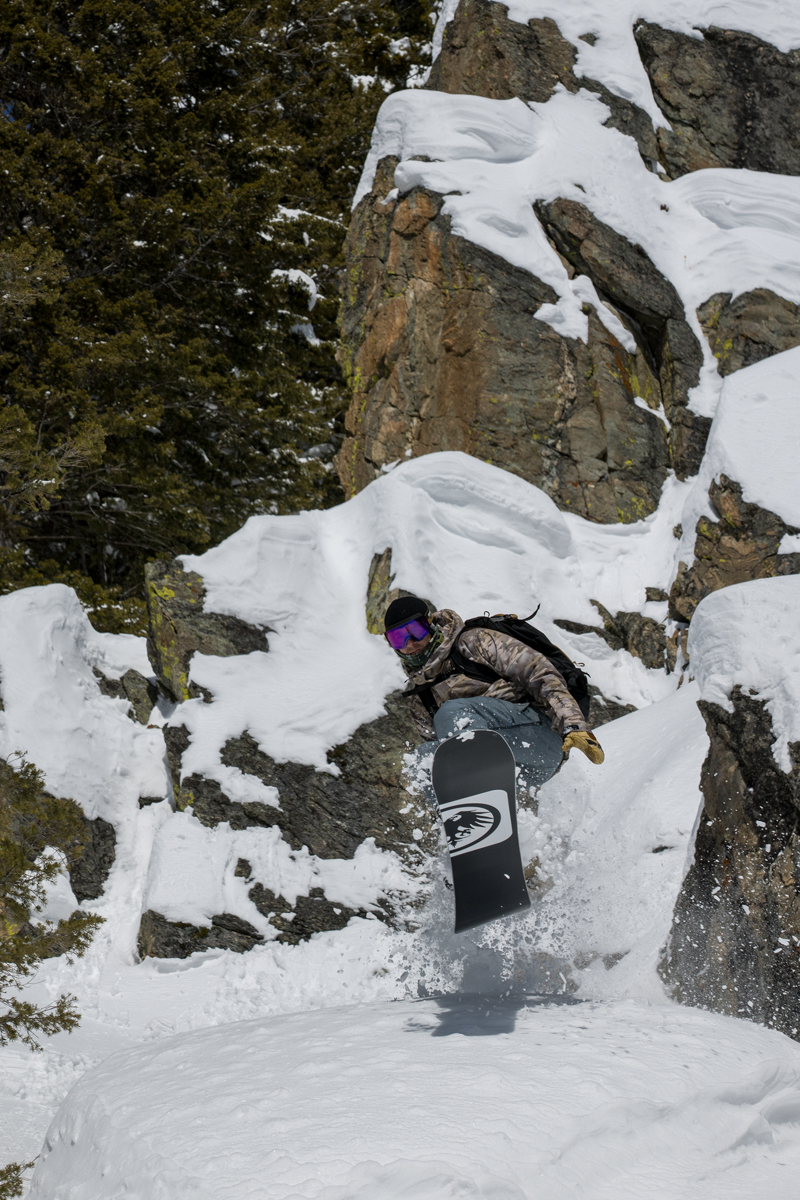 Man Snowboarding in Rocky Terrain