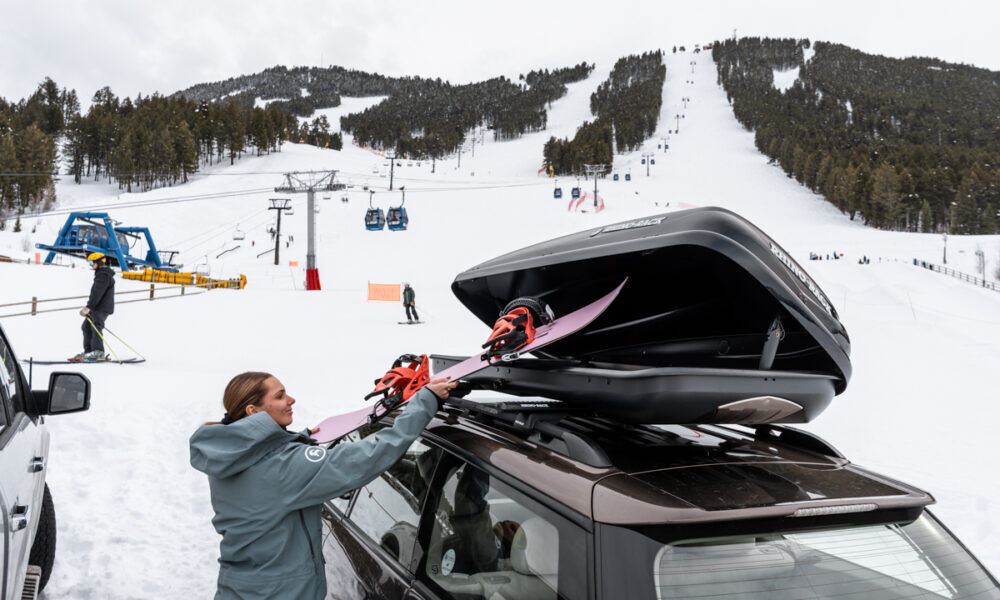 Rhino-Rack Cargo Box Review – Zenith Model Rhino Rack Roof Box Women Taking Skis Out at Base of Ski Area Off Car Cargo Carrier