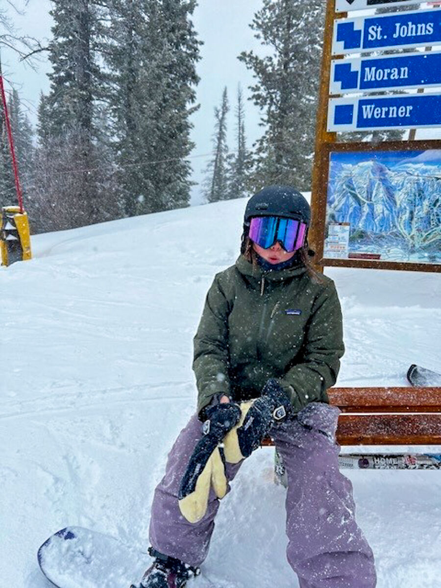 Women Sitting on a Snowboard Bench Wearing Patagonia Storm Shift Jacket