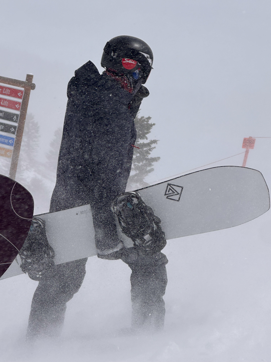 Snowboarder holding the Korua Transition Finder board during a heavy Teton snowstorm.