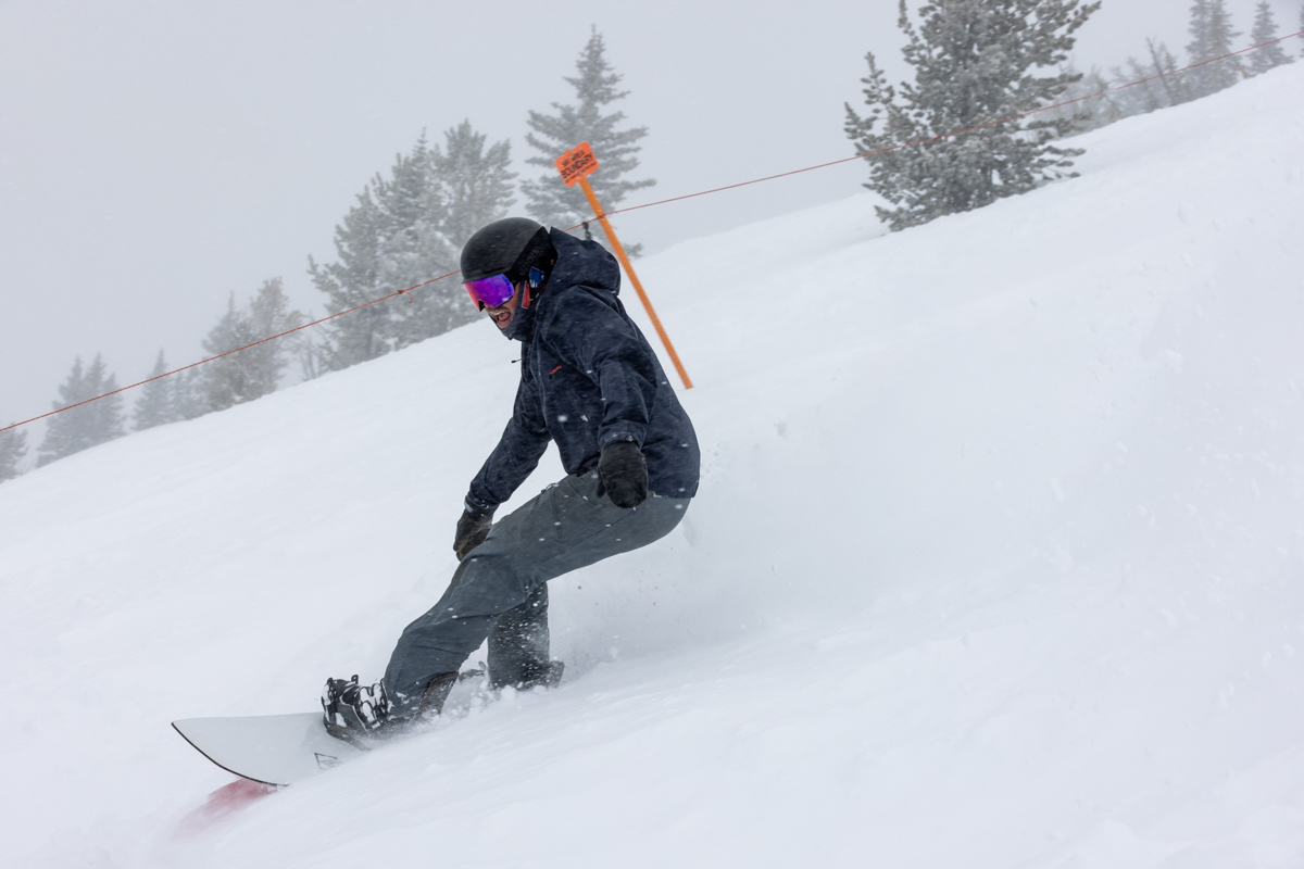Rider leaning into a carve on the Korua Transition Finder snowboard in snowy conditions.