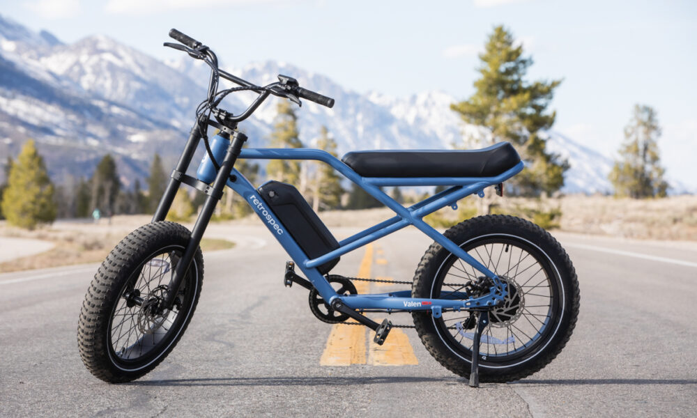Retrospec Valen Rev 3 E-Bike in Blue Against Green Trees