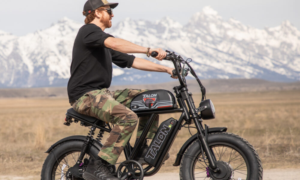 Full side profile of the Talon T87 Dual Motor E-Bike on a dusty road in Jackson Hole, highlighting the moped-style frame and 20-inch fat tires perfect for gravel and dirt.