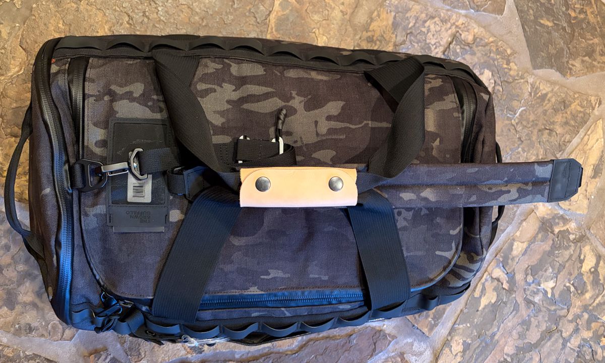 The Brown Buffalo Duffalo duffel bag technical hardware detail showing leather handle with industrial snaps and premium D-ring attachment