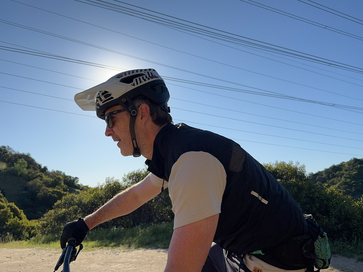 Cyclist testing the Canyon Deflectr Trail helmet on a sunny ride, highlighting field-of-view and visor coverage for high-output mountain bike TETON Tested Review