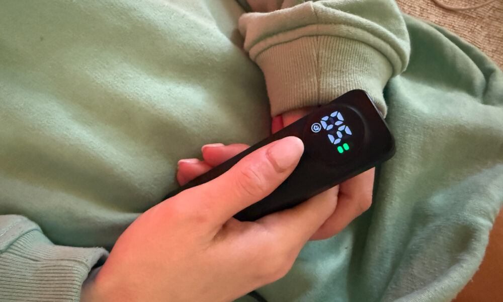 Hand holding the EZ-Life red light therapy mask remote controller showing 5-minute timer