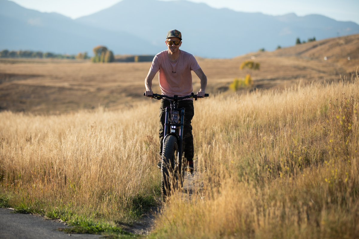 Mike Hardaker field testing the Mokwheel Onyx full suspension e-bike on a rugged dirt and gravel path in the Wyoming backcountry.