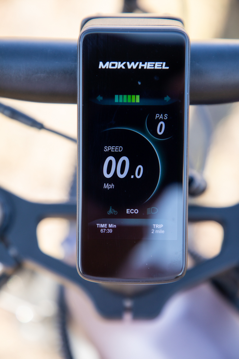 The digital LCD handlebars display screen on the Mokwheel Onyx electric bike during an off-road technical gear review.