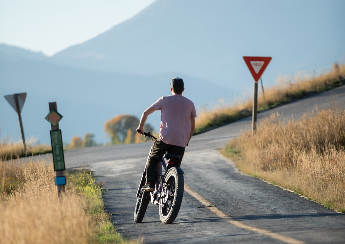 Mokwheel Onyx fat tire e-bike being tested on a winding asphalt road, showcasing its versatile performance as a mountain commuter.