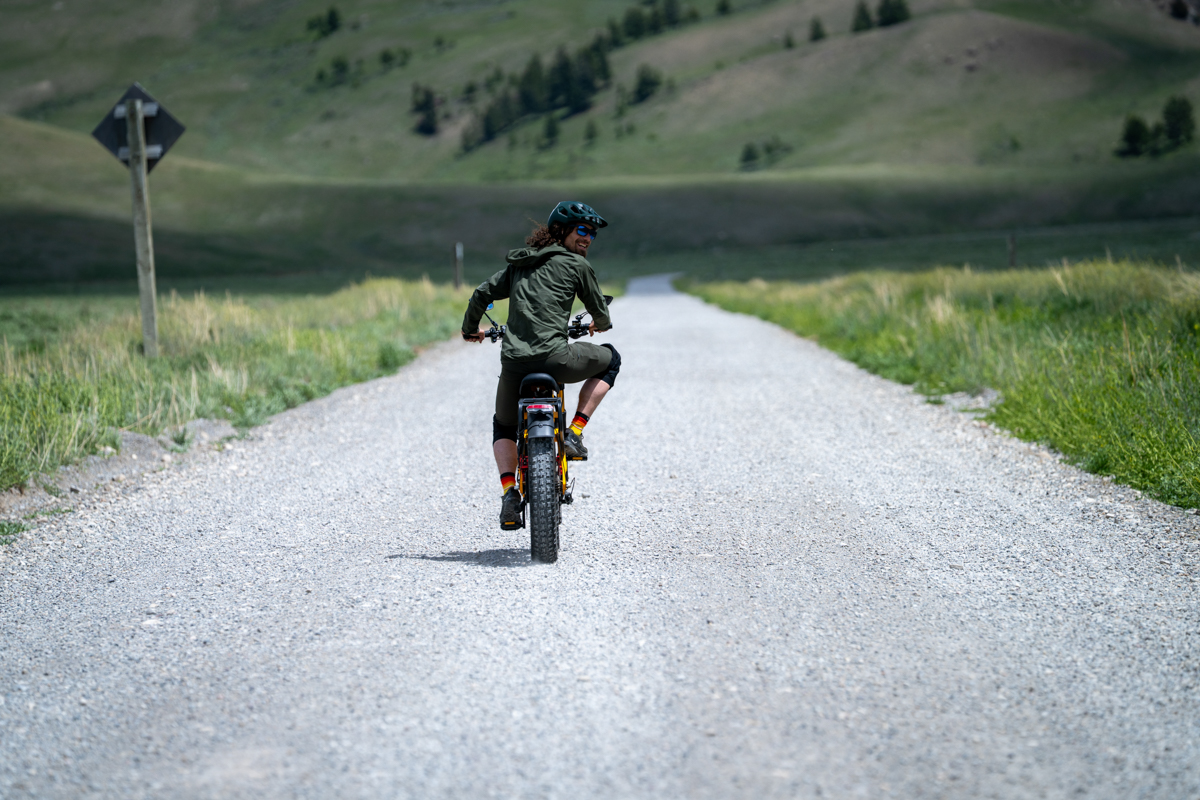 Rear view of Pat Kinney riding the Aniioki A9 Pro Max down a gravel road in Jackson Hole with mountain scenery ahead.