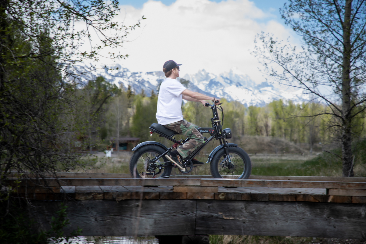 Mike Hardaker riding the Talon T757 across a bridge with Grand Teton views in Wyoming