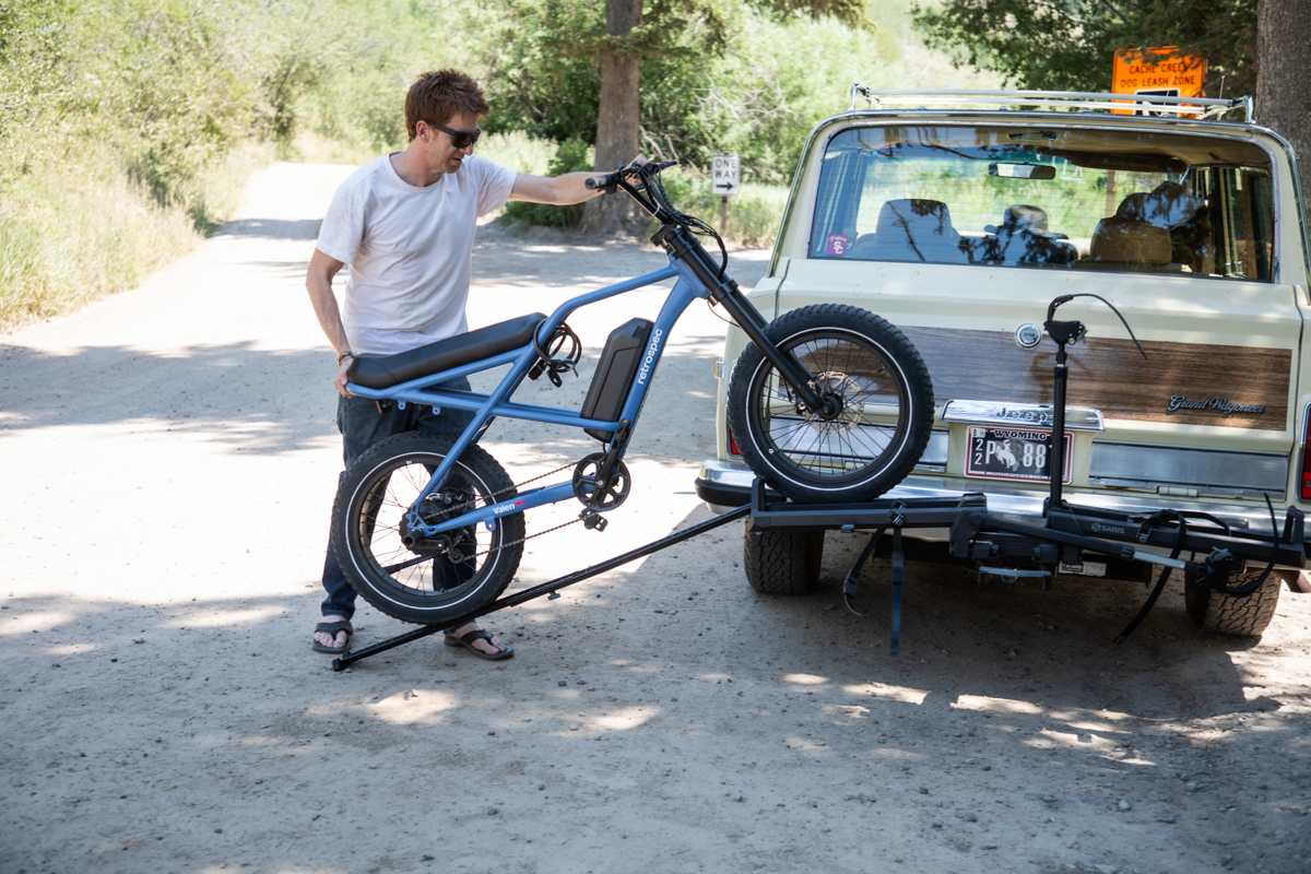 Person lifting an electric bike toward the Saris Cycle-On bike rack.